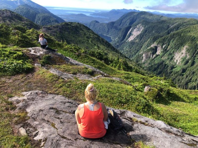 woman sitting out on a mountain peak and gazing out into the distance