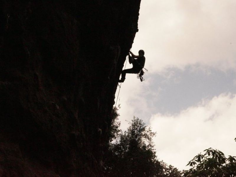 man geared up in a harness and rock climbing