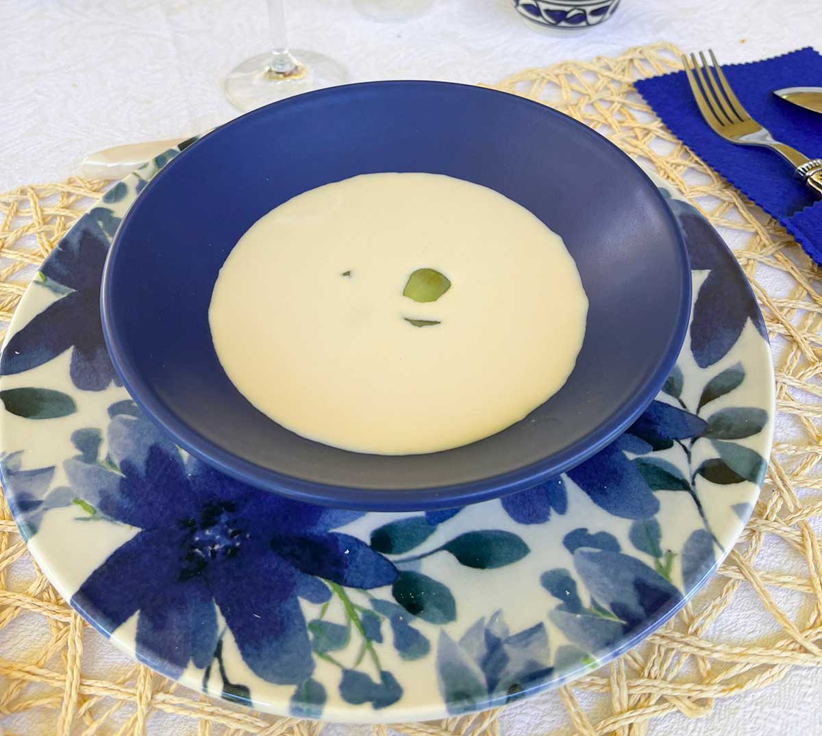 Ajoblanco, a Spanish vegan dish featuring a cold almond and garlic soup, served with a grape in the center.