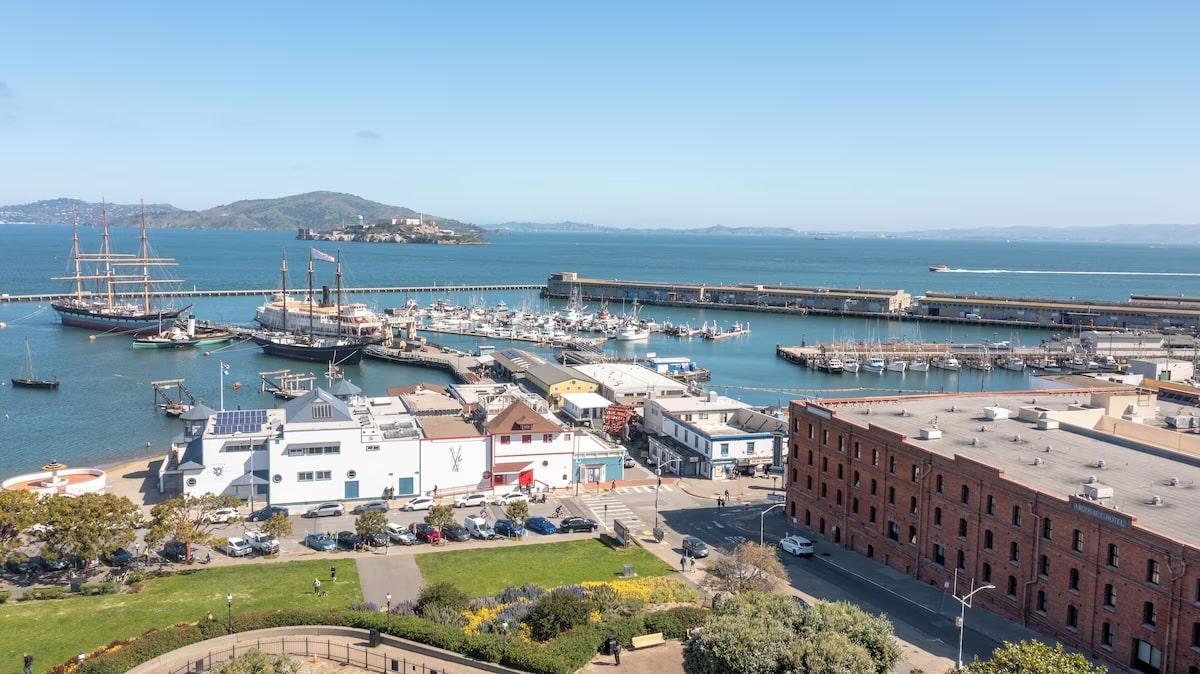 A scenic view from the vegan Argonaut Hotel in San Francisco, showcasing Fisherman’s Wharf, historic ships docked in the harbor, and the distant outline of Alcatraz Island on a clear day.
