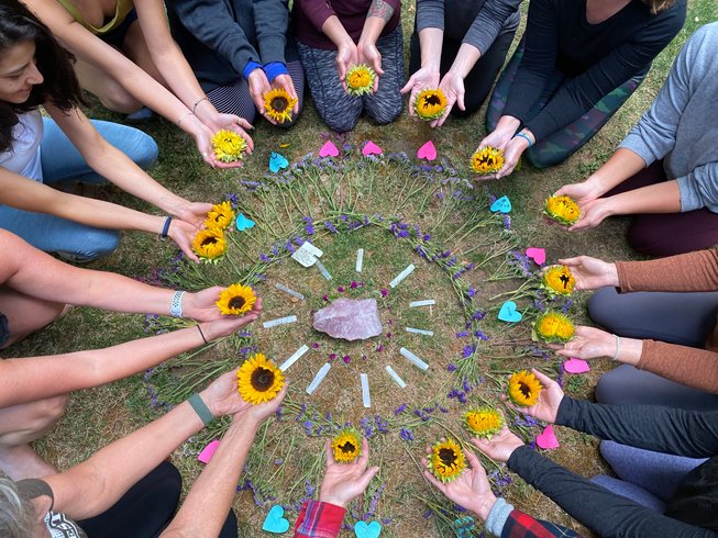 group of people sitting in a circle while holding sunflowers in their hands during a wine yoga retreat in Marcola, Oregon