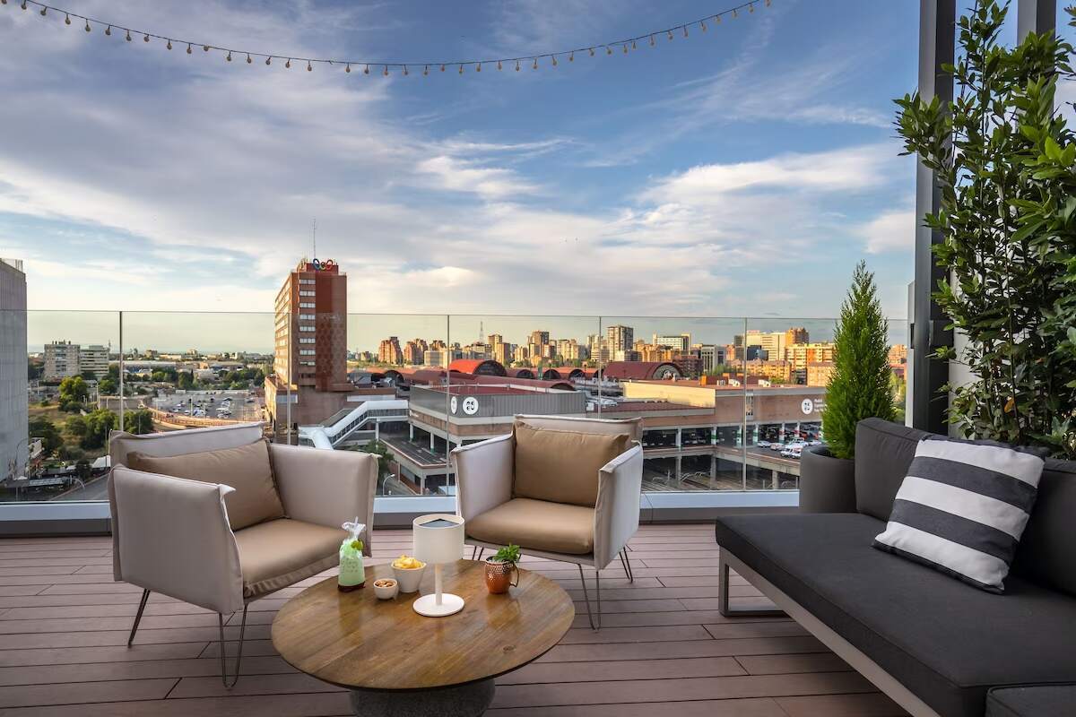 The rooftop at the Barceló Imagine Hotel in Madrid, Spain, featuring comfortable seating and a panoramic view of the city.