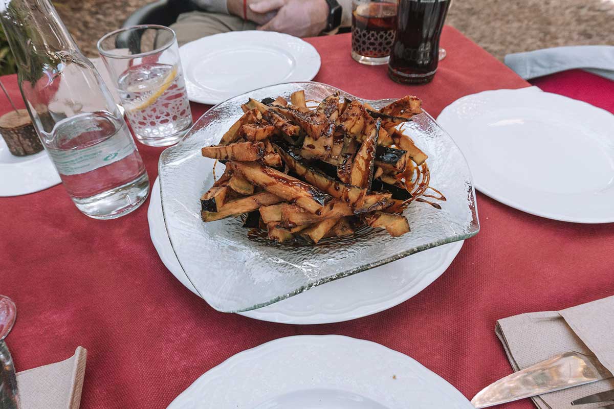 a white plate featuring fried aubergine with sugar cane honey
