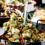 A vibrant assortment of vegan dishes including roasted fennel, mixed salads, and fresh vegetables