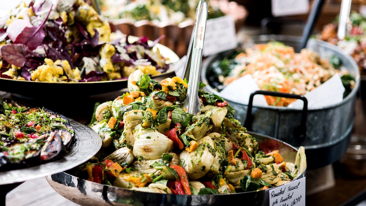 A vibrant assortment of vegan dishes including roasted fennel, mixed salads, and fresh vegetables