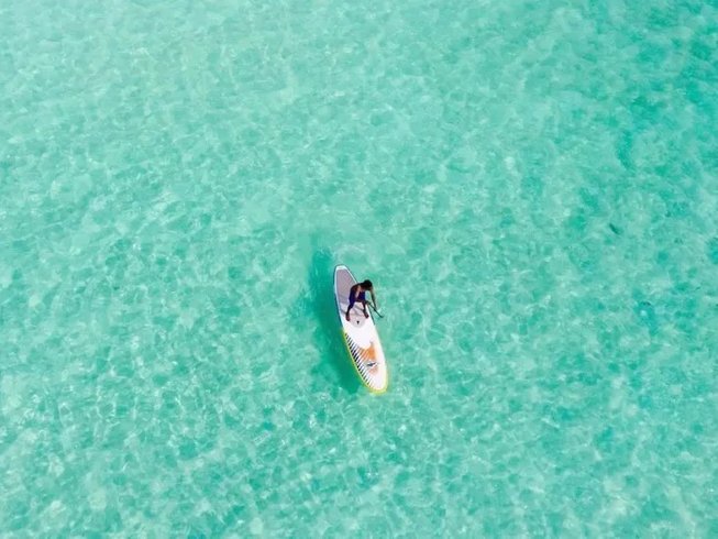person stand up paddle boarding in clear turquoise waters
