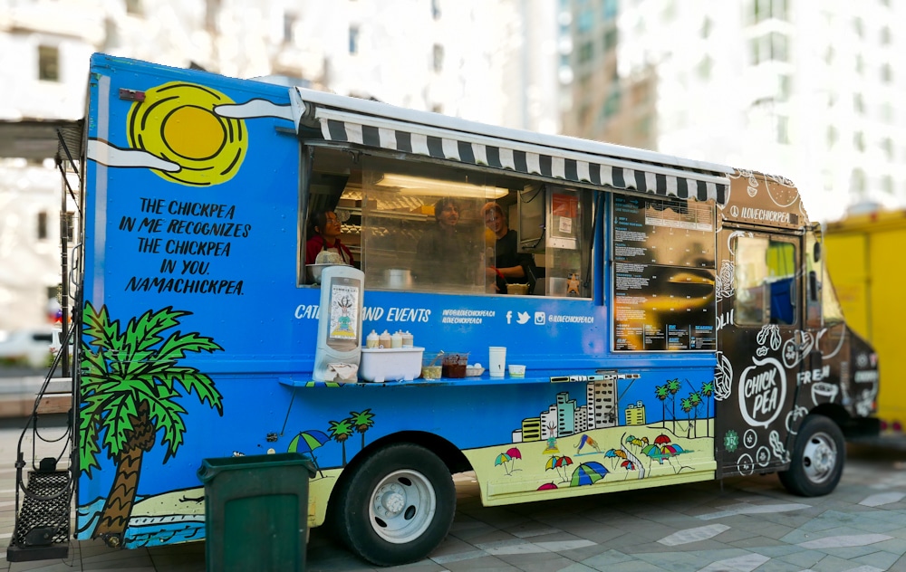 the blue and yellow vegan Chickpea food truck sits in a parking lots in Vancouver
