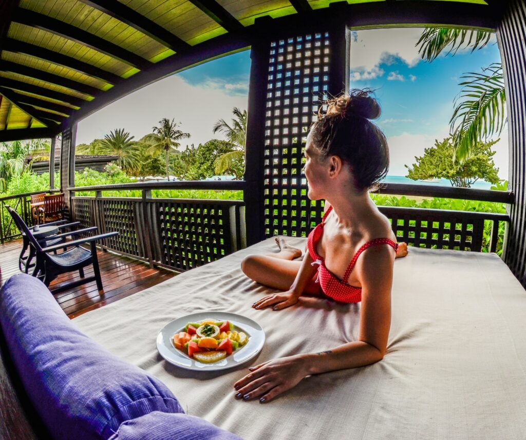 woman eating a plate of fresh fruit at the vegan-friendly Hermitage Bay Resort in the Caribbean