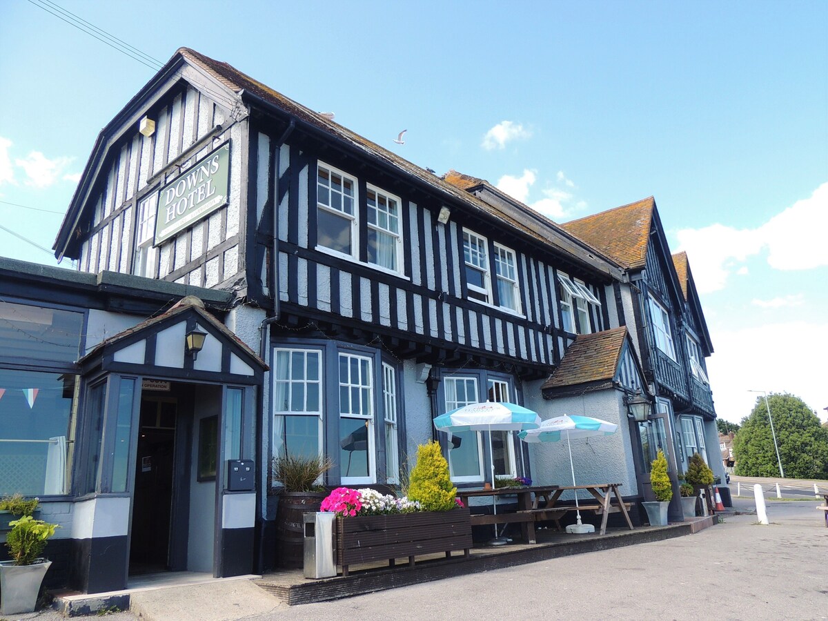exterior view of The Downs vegan hotel in Brighton showcasing a pitched roof and flower-filled patio