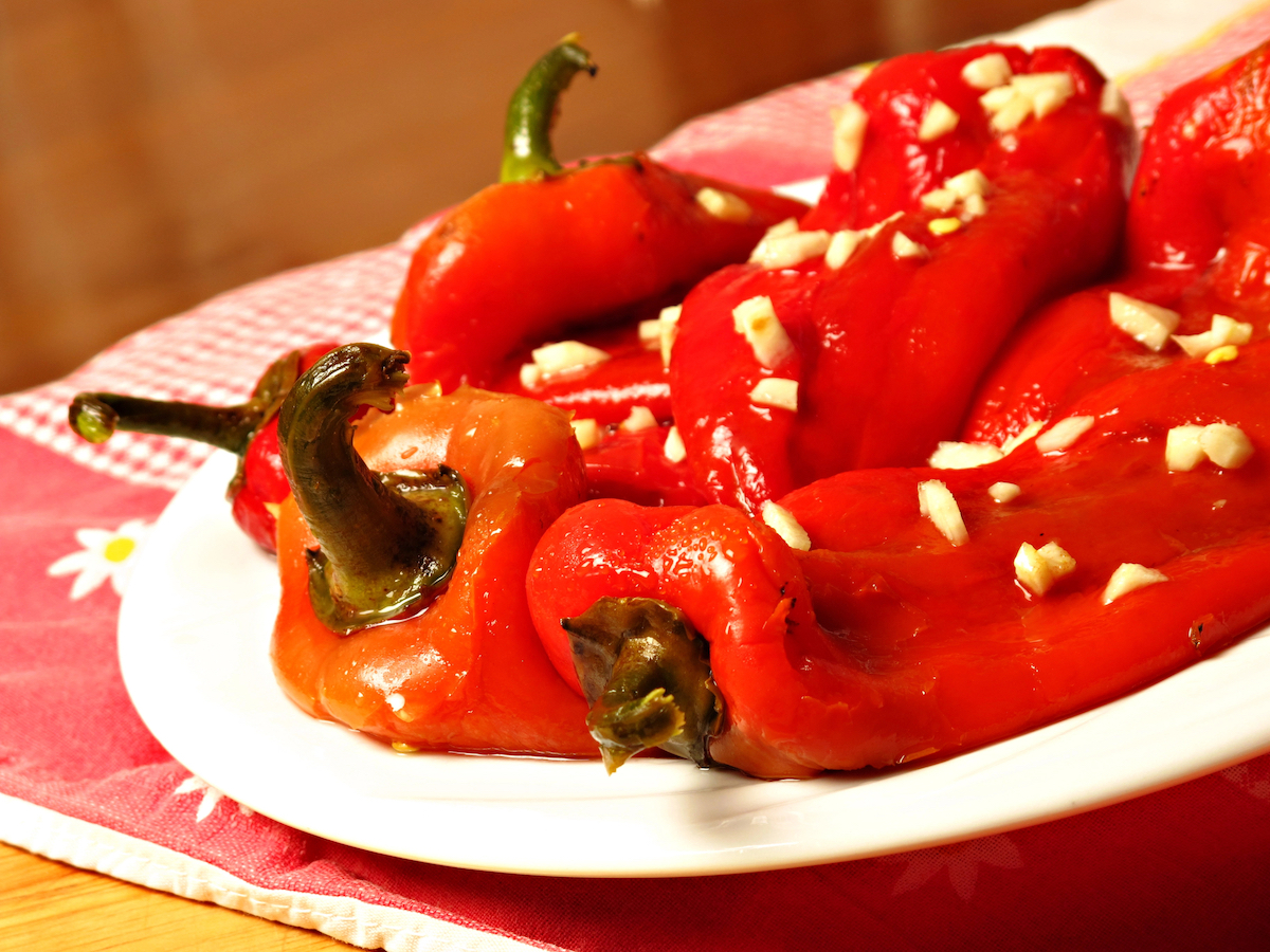 Ensalada de Pimientos, a delicious vegan Spanish dish featuring roasted red peppers topped with chopped garlic.