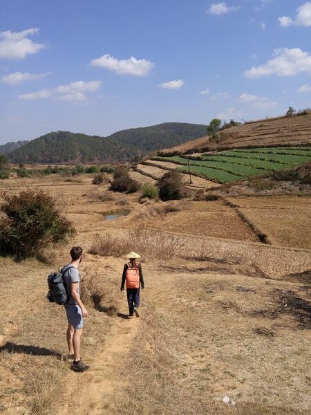 travelers hiking past terraces fields and rolling hills on the trek from Kalaw to Inle Lake