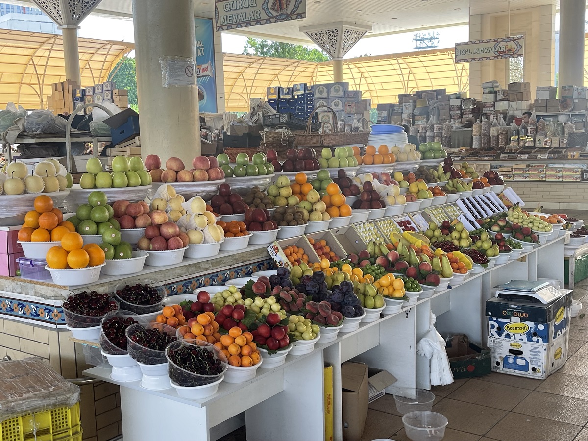 A vibrant display of fresh fruits at Tashkent's Alay Bazaar in Uzbekistan, featuring a variety of apples, pears, oranges, cherries, and other seasonal produce. An excellent spot for finding fresh ingredients for vegetarian dishes.