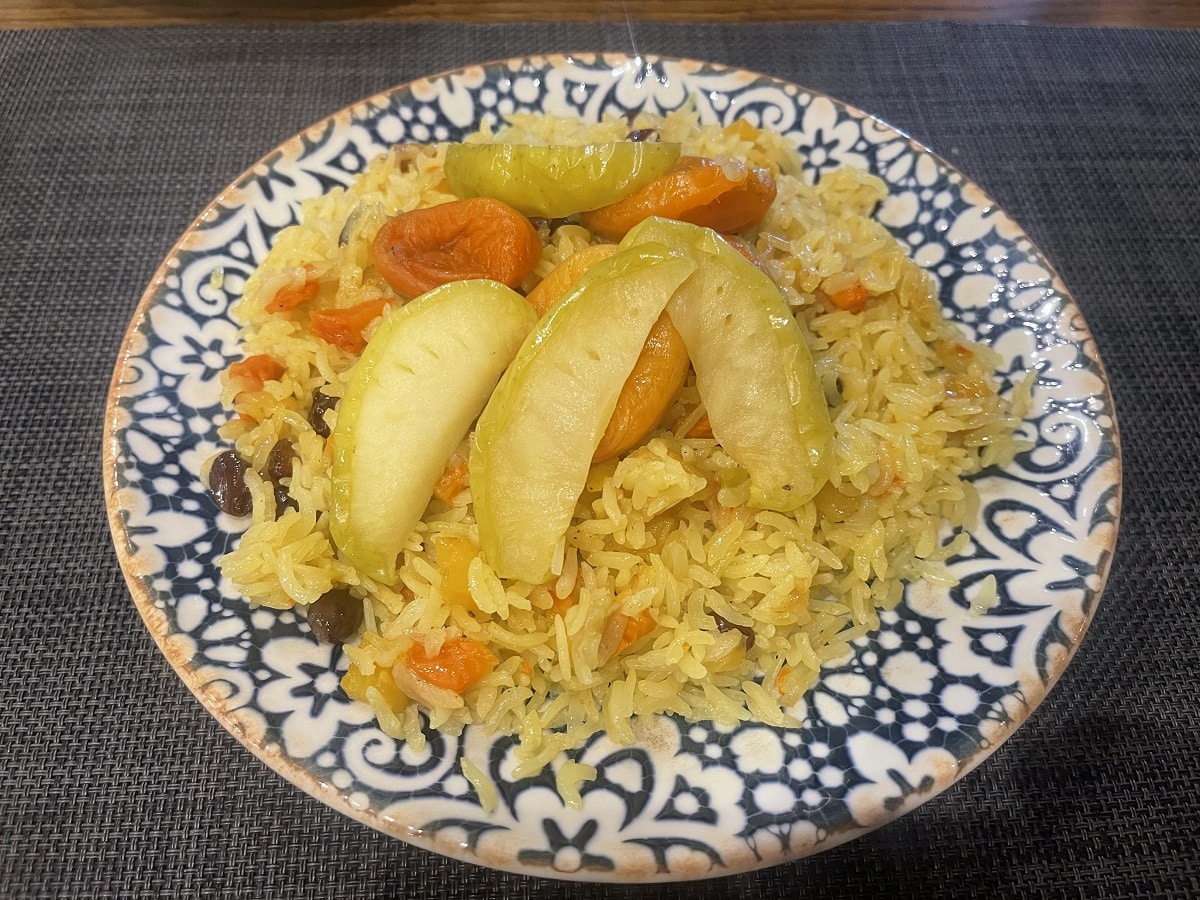 A beautifully presented plate of vegetarian-friendly fruit plov served at the Afsona vegetarian restaurant in Uzbekistan. This dish features vibrant rice mixed with various fruits, highlighting the delicious vegetarian options available in Uzbek cuisine.