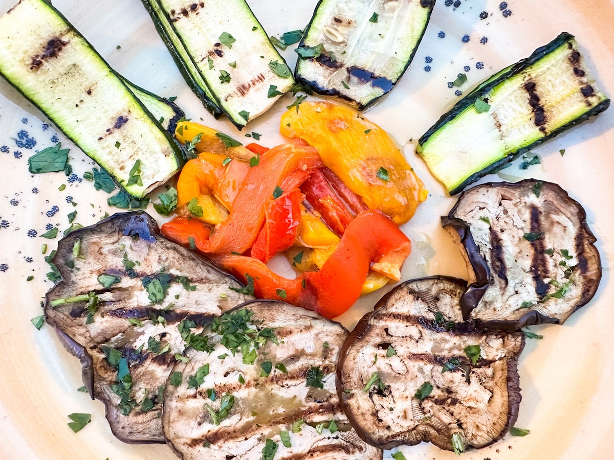 Verdure alla griglia, a colorful Italian vegan side dish featuring grilled zucchini, eggplant, and bell peppers, garnished with fresh parsley on a ceramic plate.
