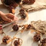 person making their own holiday decorations using string and pinecones