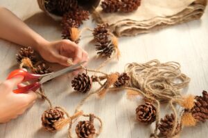 person making their own holiday decorations using string and pinecones
