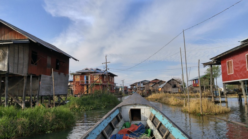front of boat pointing to local homes on stilts on Inle Lake