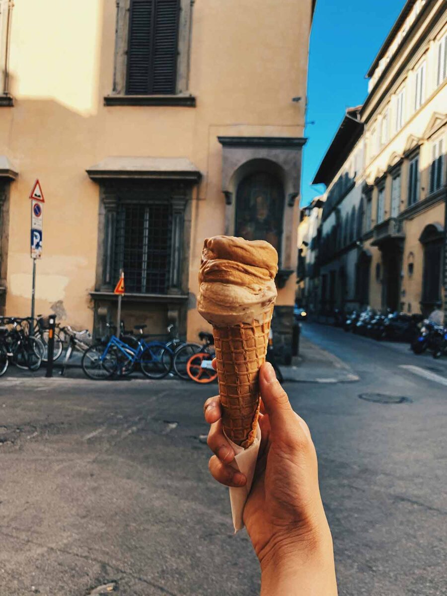 A person holding a gelato in a street of Florence.