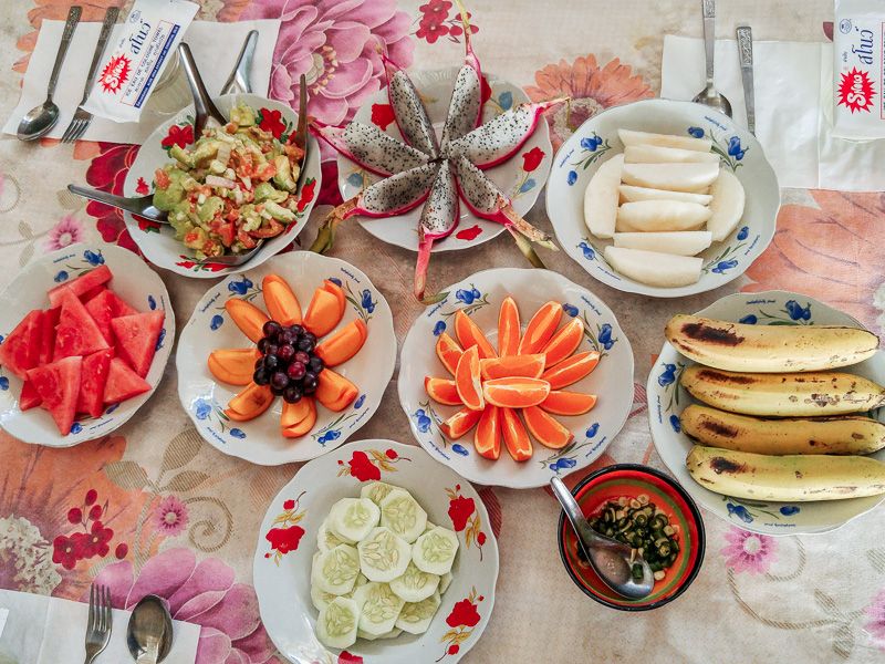 table spread of fresh fruits and vegetables including bananas, dragon fruits, watermelons, avocados, and cucumbers in Myanmar
