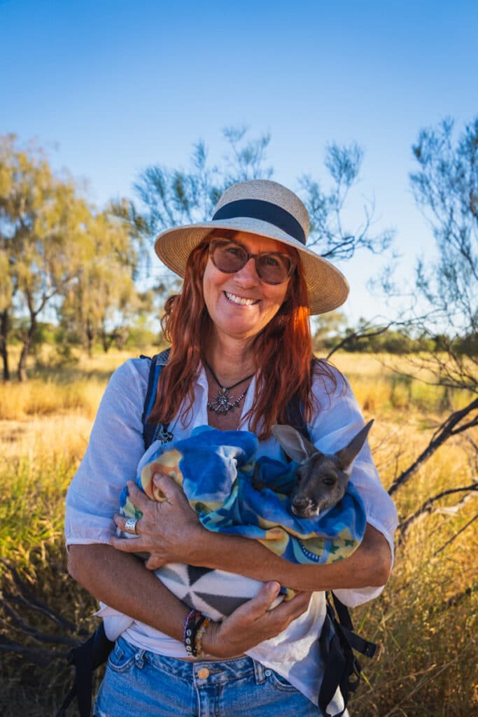 woman holding a baby kangaroo while volunteering at the Kangaroo Sanctuary in Alice Springs, Australia