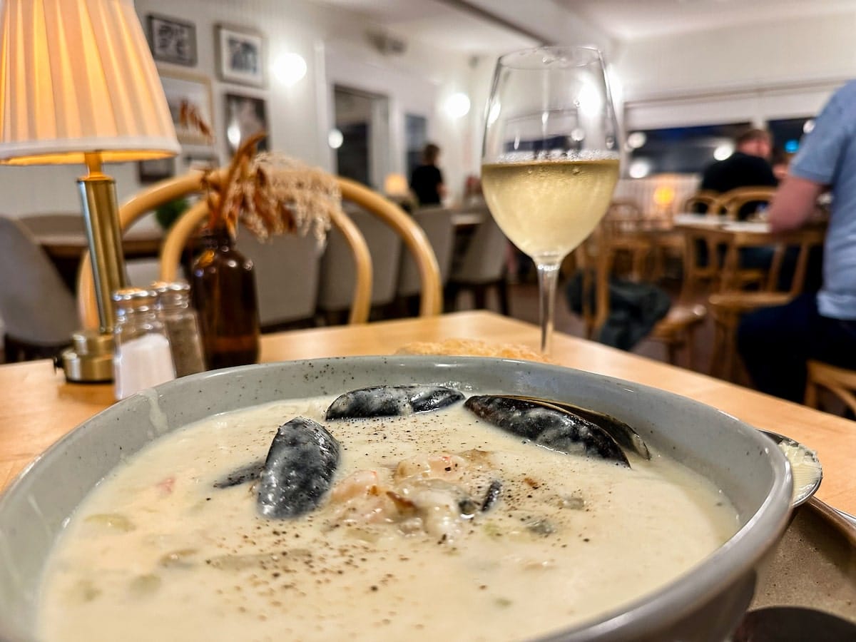 A bowl of creamy seafood chowder paired with a glass of Tidal Bay wine at Longfellow Restaurant in Grand Pré, Nova Scotia.