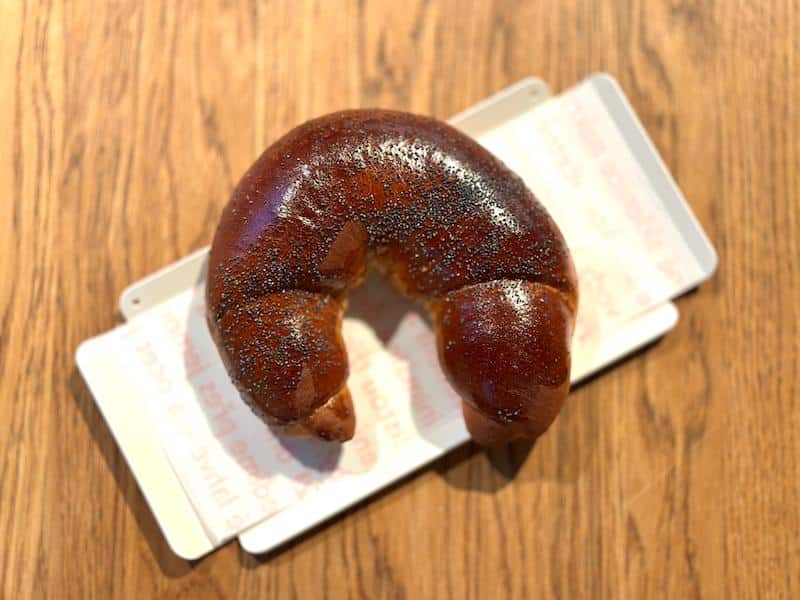 woman eating a half-moon shaped loupák at a bakery in Prague