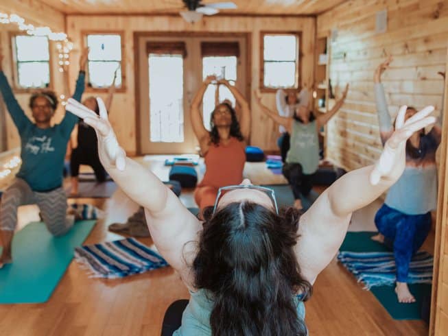 group of women practicing yoga in a room with wooden walls and floors during a yoga wine retreat in Mineola, Texas