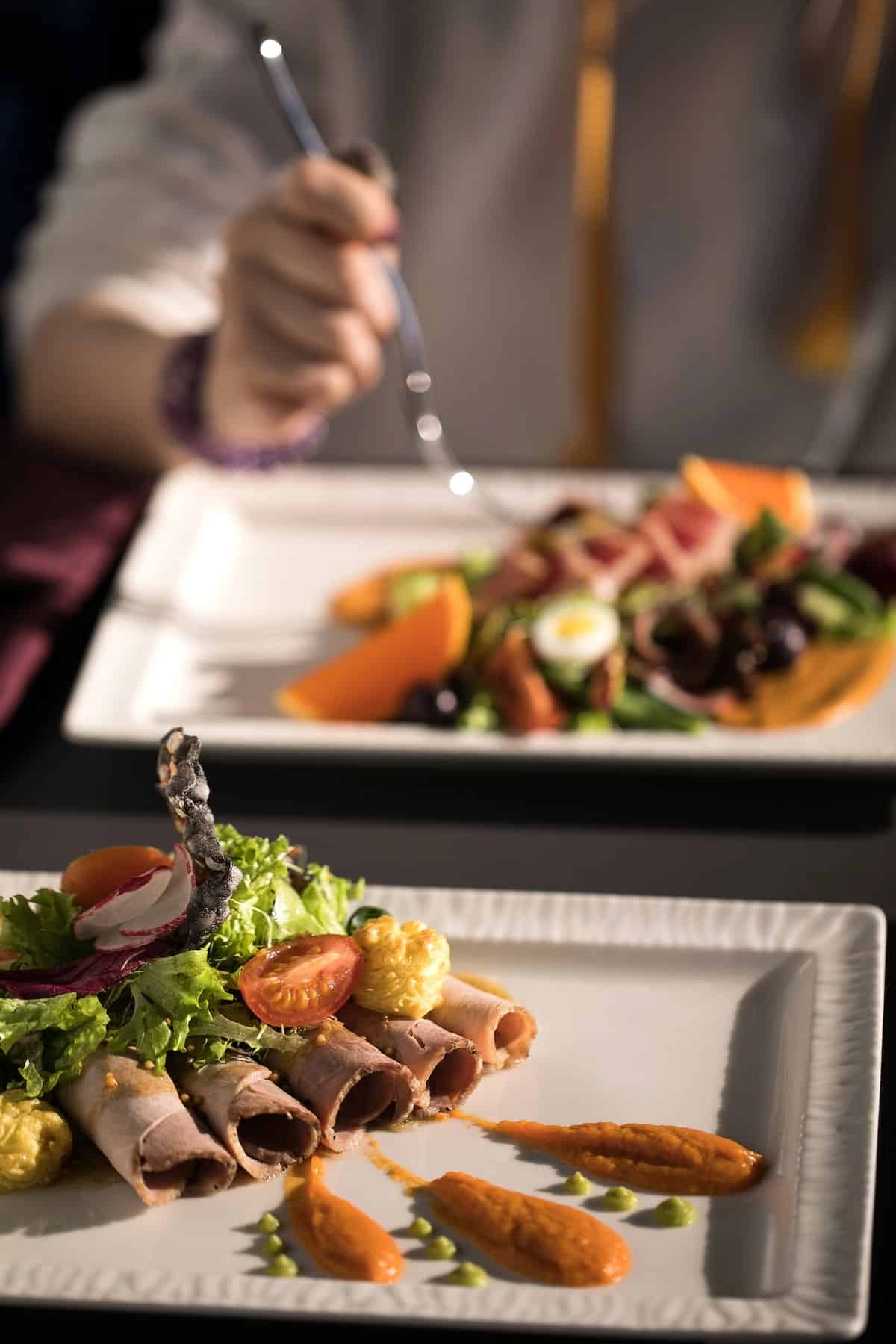 unique dishes featuring a variety of meat and vegetables served on white plates at a communal tasting table