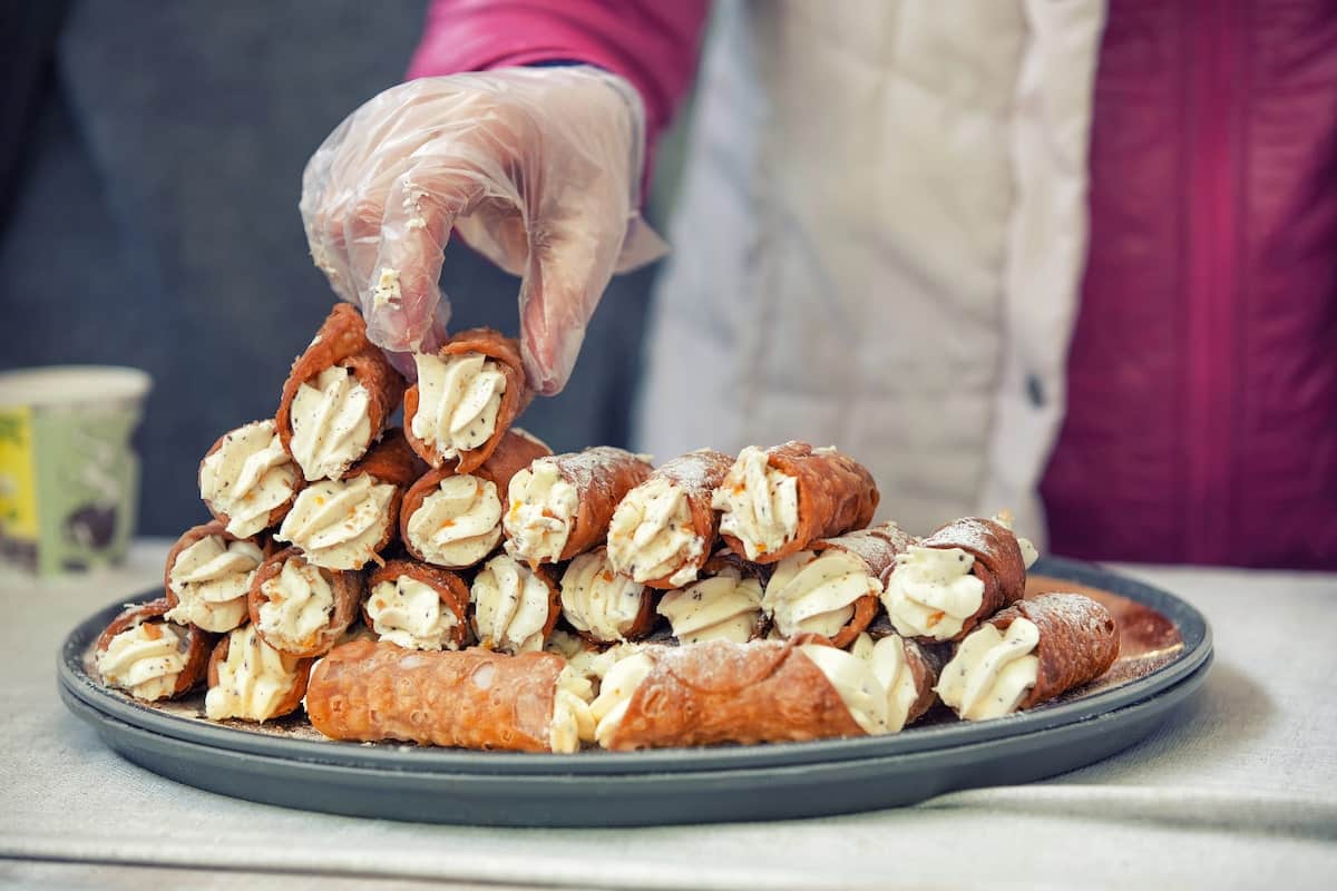 pastry chef in Sicily putting fresh cannolis on a tray