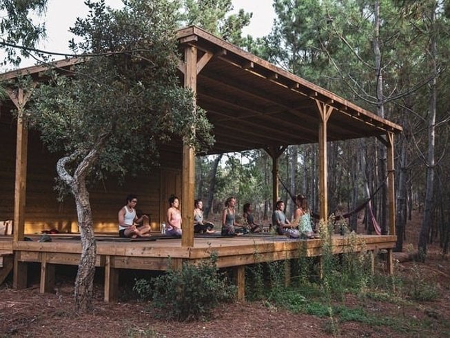 group of people sitting in lotus pose on an outdoor deck during a wine and yoga retreat in Cercal do Alentejo, Portugal