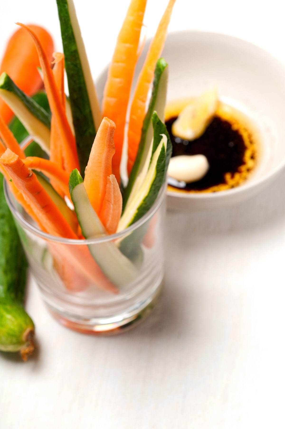 Glass filled with raw vegetable sticks including carrots and cucumbers, served with a small dish of olive oil and garlic for dipping — a traditional Italian appetizer known as pinzimonio.
