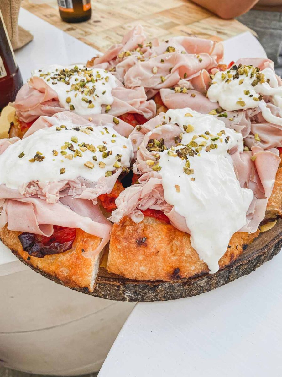 Pizza with cheese, mortadella and pistachio.