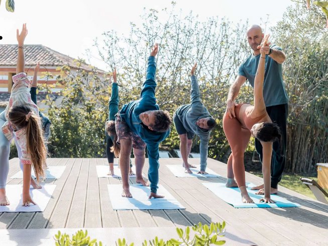 group of yogis in Triangle Pose on an outdoor deck during a Rebalancing Yoga Retreat in Scansano, Italy