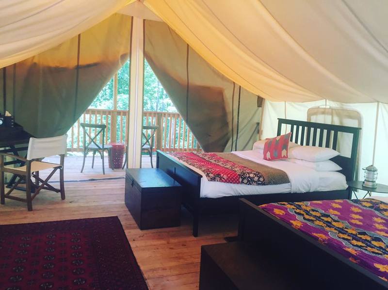 glamping tent with two beds, a desk, and a patio set up for a Glamping Yoga Retreat at Firelight Camps, hosted by Finger Lakes Yogascapes