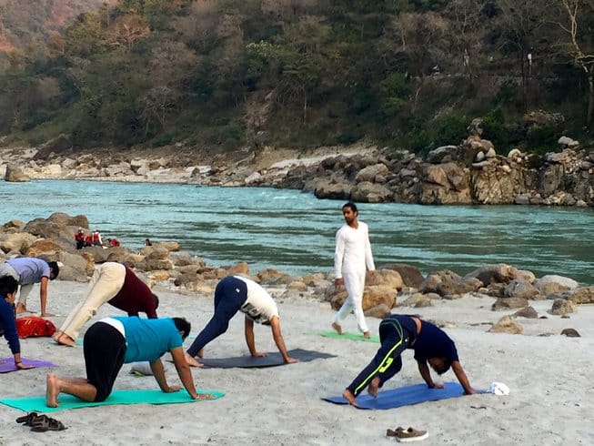 group of people doing yoga on the beach during a Shiva Shakti Meditation and Yoga Retreat in Rishikesh, India