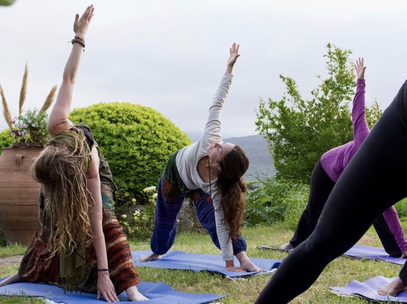 women doing yoga in the grass while on a yoga getaway in Greece