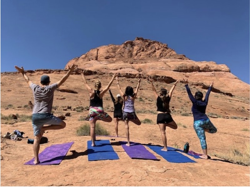 women standing on yoga mats among red rock cliffs during a spiritual yoga retreat in Arizona