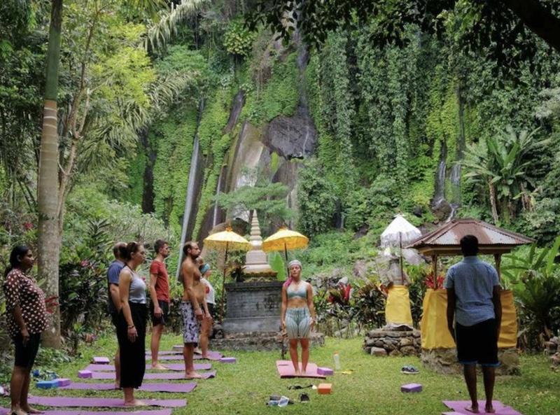 group of people standing on purple mats while surrounded by tropical plants on a spiritual yoga retreat in Bali