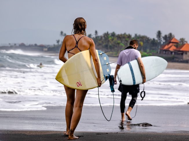 two people carrying surf boards along the beach in Bali