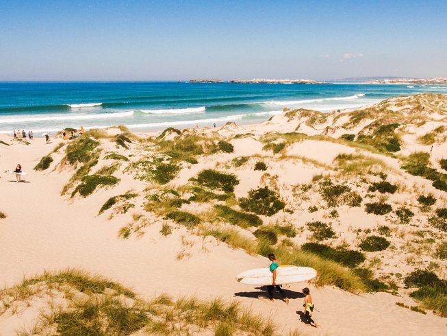 people walking along the beach holding surf boards