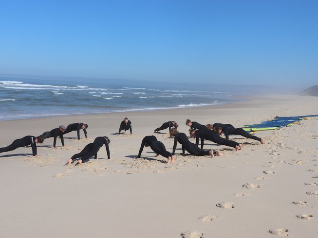 group of people listening to a surf instructor on the beach