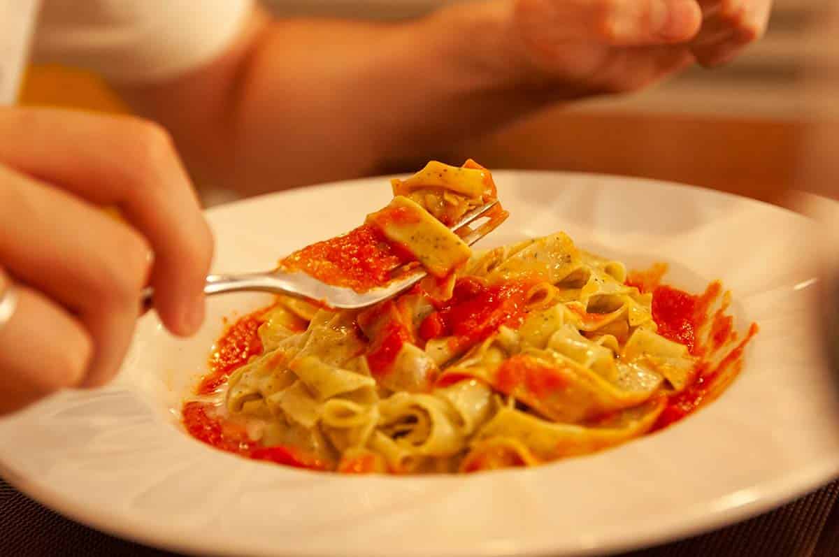 A close up photo of a person eating tagliatelle pasta.