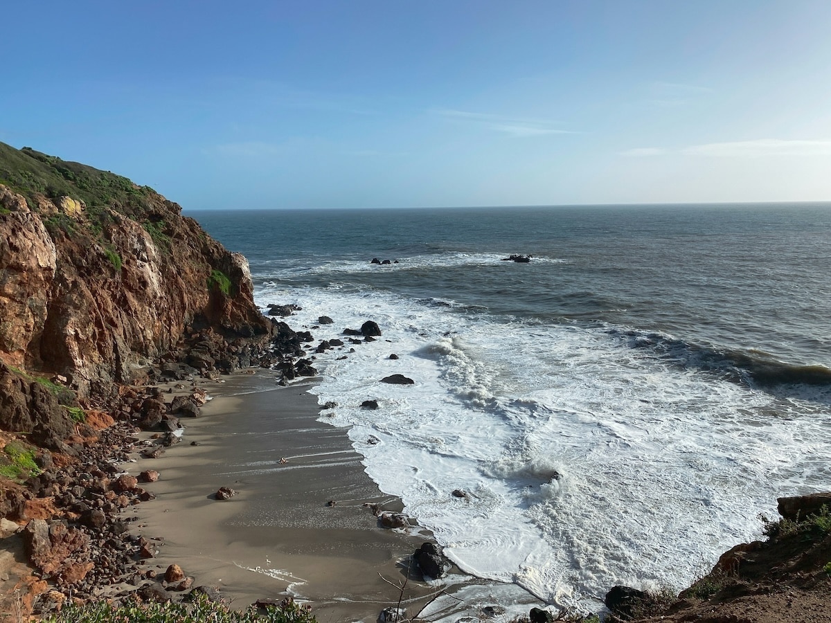 A pristine beach near The Ranch Wellness Retreat in Malibu, California, with golden sands, gentle waves, and scenic coastal views.
