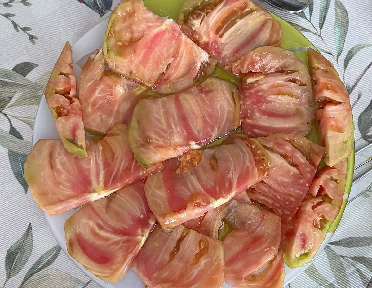 Tomate Aliñado, a vegan Spanish dish featuring fresh sliced tomatoes dressed with olive oil and salt.