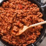 pan of Ragù Bolognese being stirred with a wooden spoon