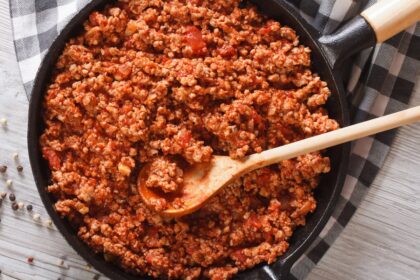 pan of Ragù Bolognese being stirred with a wooden spoon