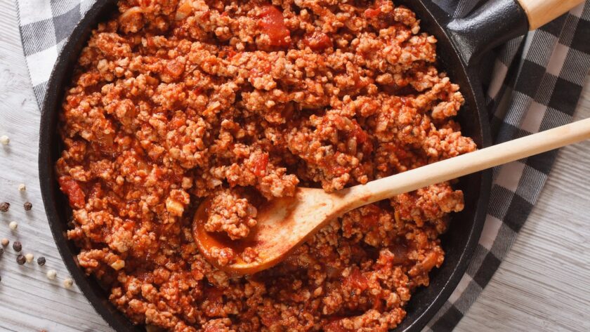 pan of Ragù Bolognese being stirred with a wooden spoon