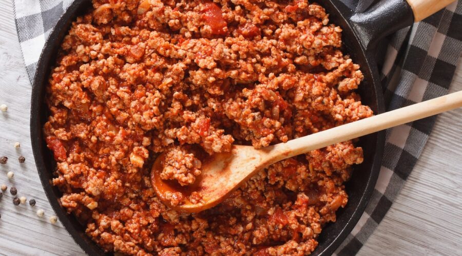pan of Ragù Bolognese being stirred with a wooden spoon