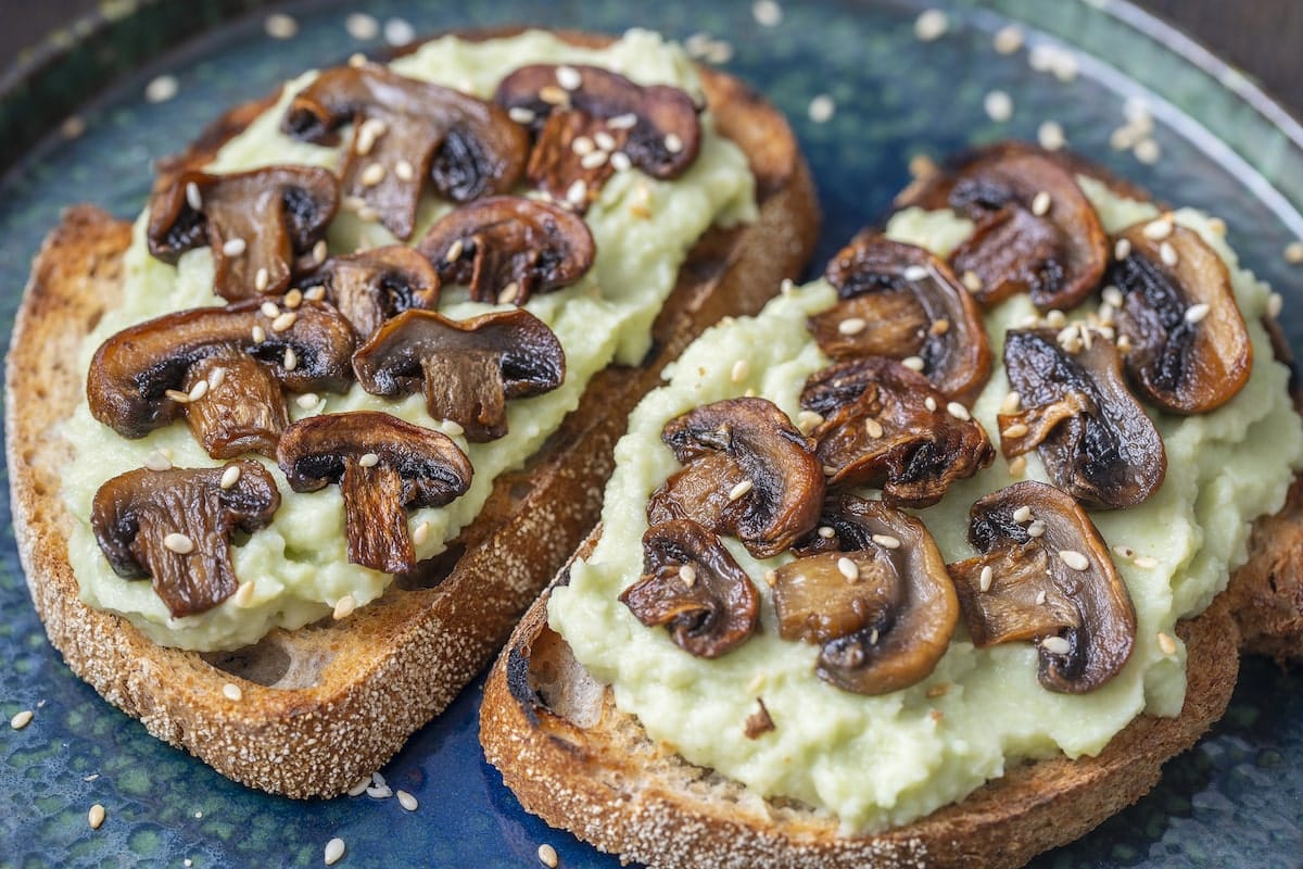 vegan avocado toast topped with mushrooms on a blue plate