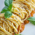vegan pasta dish in Italy topped with black pepper and basil on a white plate